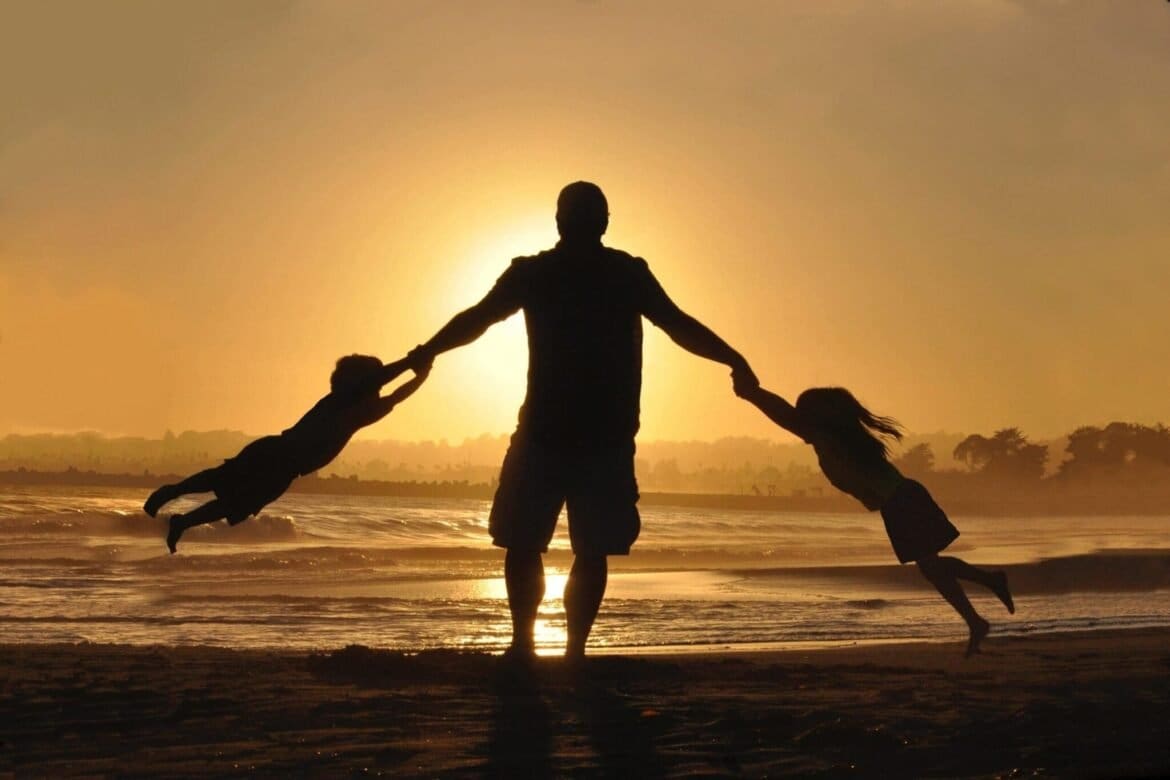 Family silhouette on beach by ocean