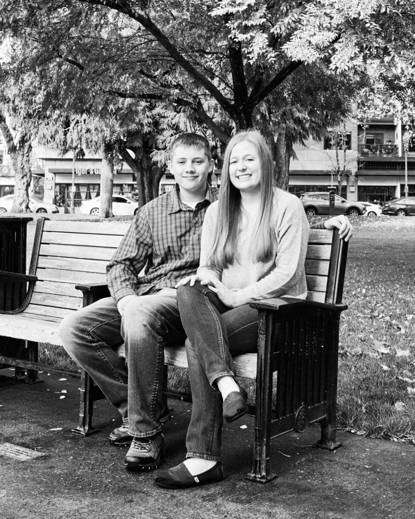 Two young adults, brother and sister, sitting on a park bench in Vancouver, Washington.
